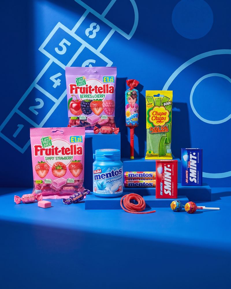 Lollipops, mint rolls and chewy sweets in a colourful spread, on a cobalt blue background.